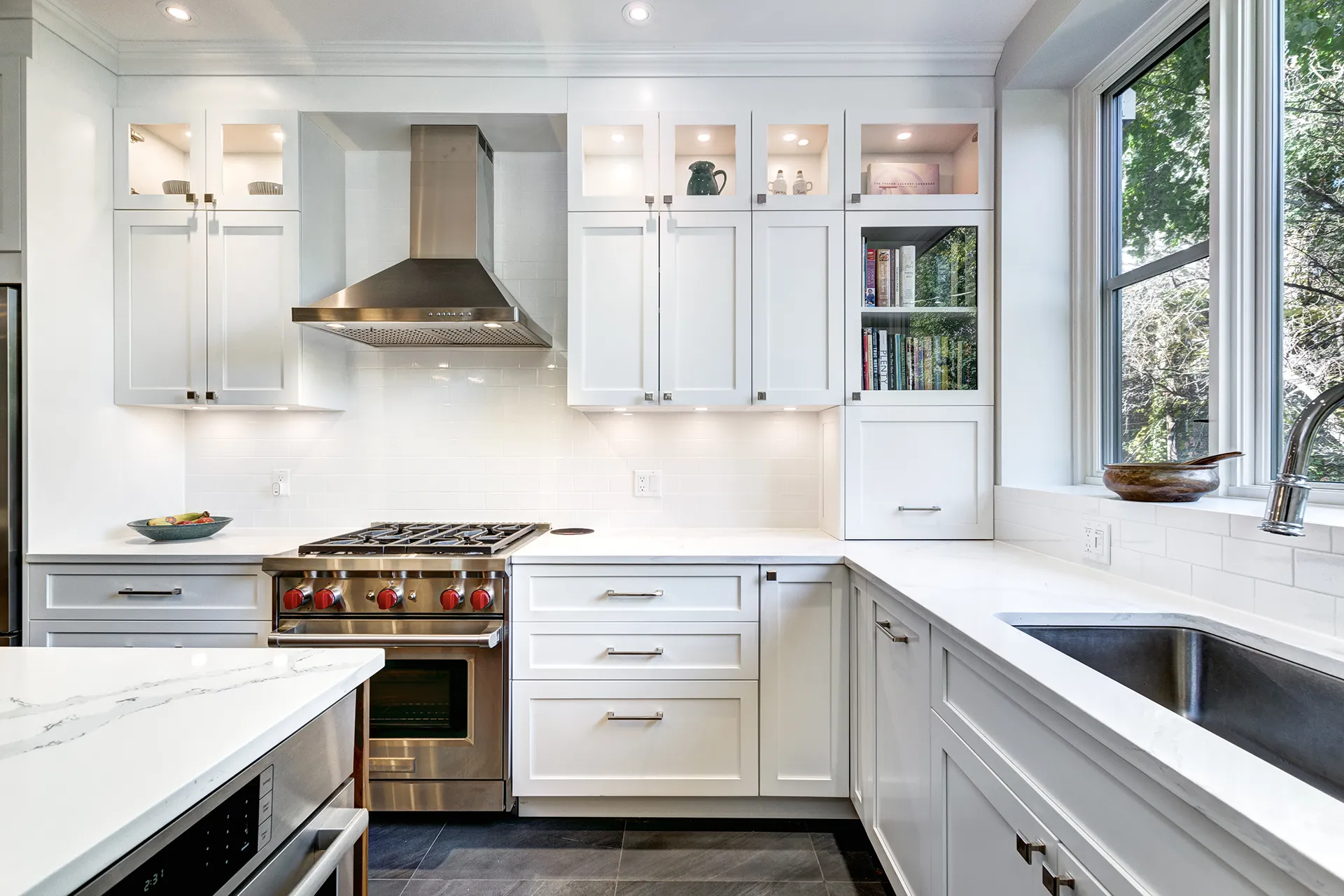 Contemporary white kitchen with Shaker cabinets, stainless steel range hood, professional stove, and white subway tile backsplash