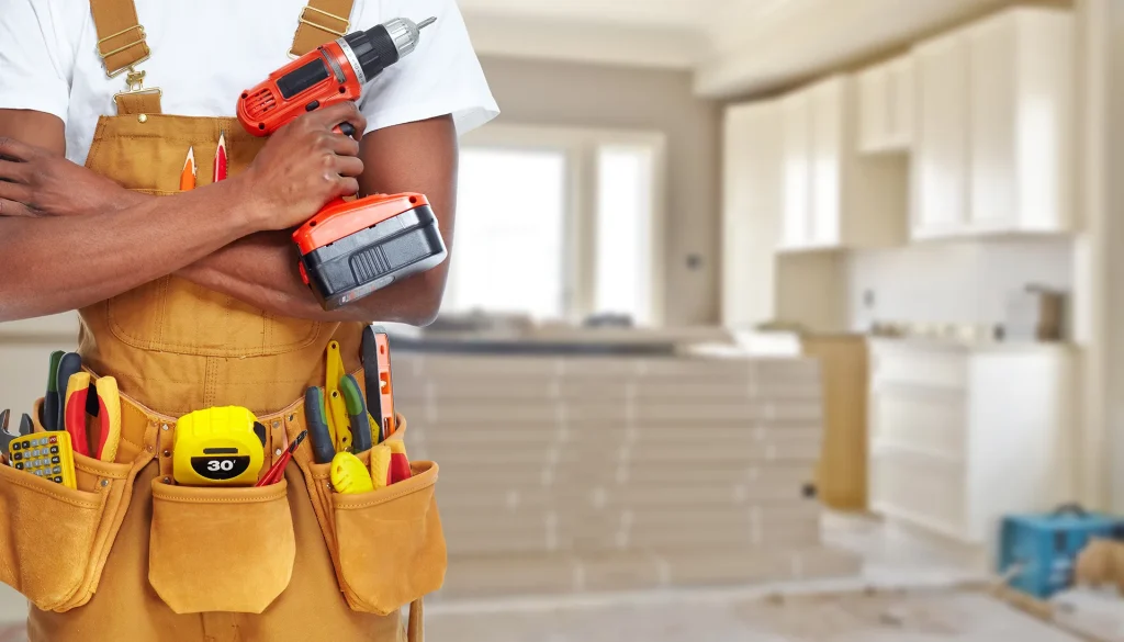 handyman holding cordless drill with tool belt and tape measure